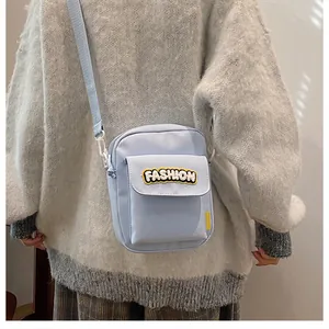 Close-up of light blue small nylon crossbody bag with fashion patch on adjustable strap