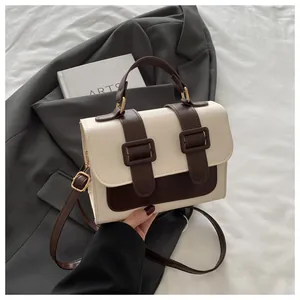 Detail of a two-tone crossbody square bag in cream and brown faux leather with top handle
