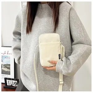 Nahaufnahme der beigen Nylon-Handytasche mit Sport-Label und verstellbarem Schultergurt
