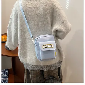 Detail of light blue crossbody phone bag with FASHION lettering and adjustable strap