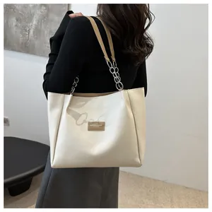 Detail of cream tote bag with chain leather straps and embossed fashion leather patch