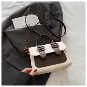 Close-up of vintage contrast handbag with gold protective studs on grey suit