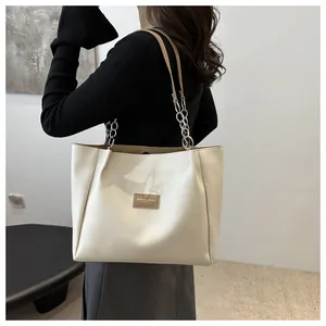 Detail of off-white tote bag featuring chain straps and brown leather fashion label