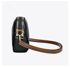 Side view detail of black litchi pattern crossbody bag with golden metal hardware