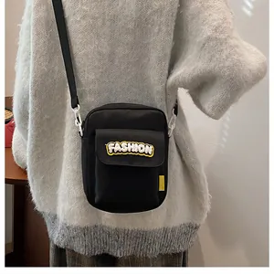 Close-up of black nylon crossbody bag featuring fashion embroidery and plastic buckles