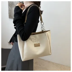 Detail of cream leather tote bag with brown leather and chain strap on a shoulder
