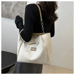 Detail of white tote bag with brown leather tag and magnetic closure mechanism