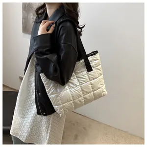 Gros plan sur le sac fourre-tout matelassé beige brillant avec bandoulière noire