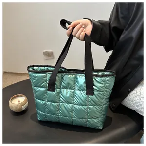 Sac fourre-tout matelassé vert brillant avec bandoulière noire tenu par un modèle