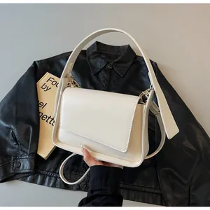 Detailopname van een crèmewitte minimalistische schoudertas met asymmetrische flap