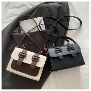 Detail view of stylish color-block and black square handbags with gold buckles on fabric