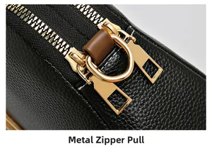 Detail of metal zipper pulls on black lychee texture leather shell bag with gold hardware