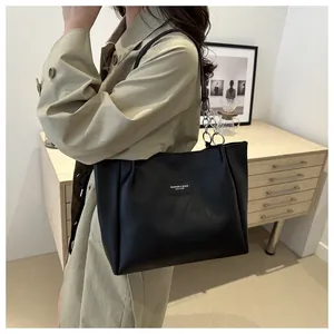 Detail of matte black leather tote bag featuring a silver chain strap and fashion logo tag