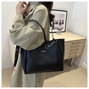 Detail of minimalist black leather tote bag with elegant metal chain shoulder strap