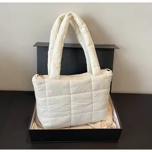 Dettaglio della borsa tote trapuntata bianca con cerniera dorata in una scatola nera