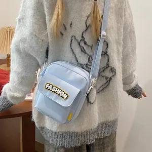 Light blue canvas crossbody bag with yellow Fashion embroidery shown on a female model
