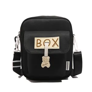 Minimalist black canvas crossbody phone bag with a cute bear charm and box label
