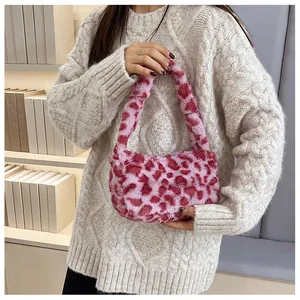 Pink leopard print faux fur handbag held by model in a cozy winter knit sweater