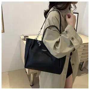 Detail of black faux leather tote bag showing pleat texture and metal chain strap