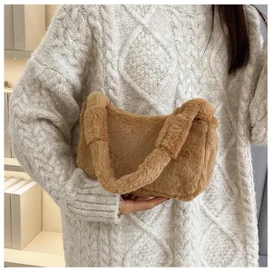 Detailed texture of a brown plush faux fur handbag held against a cozy white sweater