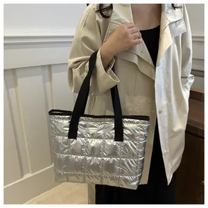 Sac fourre-tout matelassé argenté avec sangle noire porté par un mannequin chic