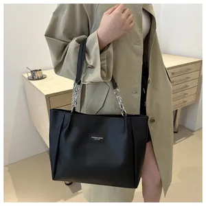 Detail of black leather tote bag featuring chain strap and fashion label on the front