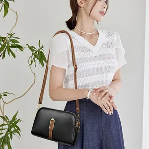 Minimalist black pebble leather shell crossbody bag with brown trim and gold hardware