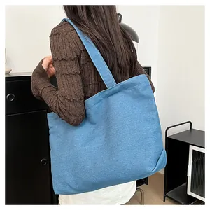 Detail of a large blue denim tote bag showing material texture and spacious design on model
