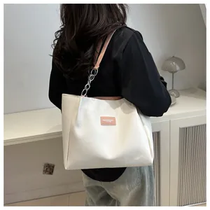 Detail of white tote bag with pink leather label and metal chain shoulder strap