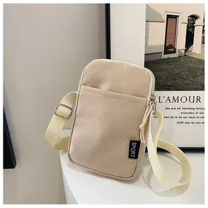Detail der beigen Cord-Handytasche mit SPORT-Label und Schultergurt