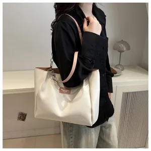 Detail of off-white tote bag featuring a brown leather patch and pink chain handle