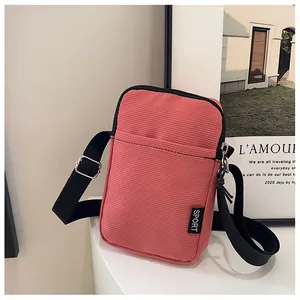 Detailansicht der rosa Cord-Handytasche mit schwarzem Sport-Logo und Textur-Details
