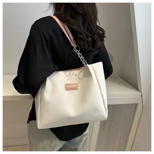 Detail of cream tote bag featuring leather shoulder strap with silver chain links