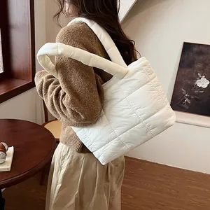 Borsa tote imbottita bianca trapuntata con spallacci spessi mostrata in una stanza