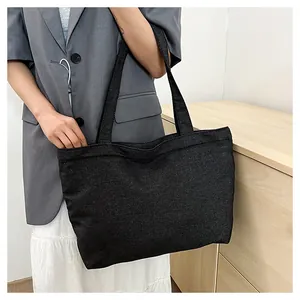 Model wearing a large capacity black denim tote bag with wide shoulder straps for commuting