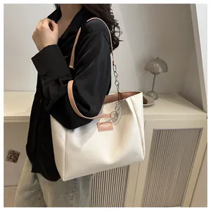 Detail of white tote bag with pink leather strap and silver metal chain decoration
