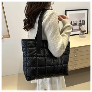 Vue latérale d'un grand cabas matelassé noir sur un modèle montrant taille et texture