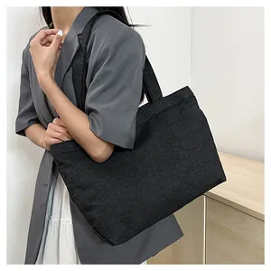 Close-up of a large black canvas tote bag with thick reinforced straps for daily commute