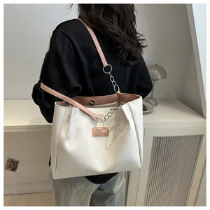 Detail of white large capacity tote bag with pink straps and decorative metal chain