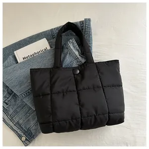 Détail du sac fourre-tout matelassé noir avec bouton pression sur linge de lit blanc