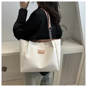 Detail of off-white tote bag with pink straps, chain decor and leather label