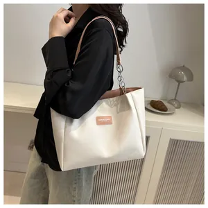 Detail of off-white tote bag featuring pink straps and decorative silver chain link accents