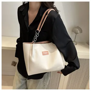 Detail of off-white tote bag with pink straps, metal chains and leather logo tag