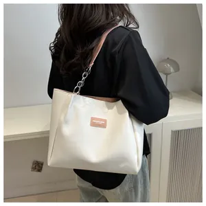 Detail view of large white tote bag with pink leather strap and silver chain on model