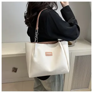 Detail of white tote bag with pink straps and silver chain worn by a female model