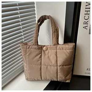 Détail de ce sac fourre-tout matelassé marron avec texture douce et bouton-pression