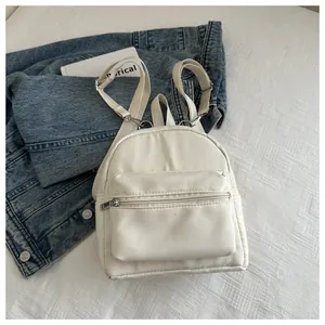 Detalle de la mini mochila de nailon blanco crema con bolsillos de cremallera en vaquero