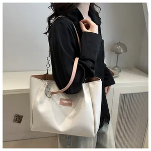 Detail of cream tote bag featuring pleated texture, leather brand tag and chain strap