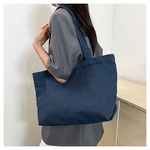 Large capacity dark blue denim tote bag shown worn on shoulder for daily commute style
