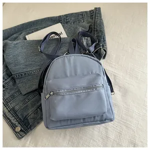 Vista detallada de una mini mochila de nailon azul grisáceo sobre fondo blanco